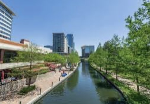 Waterway in The Woodlands, TX with high-rise buildings and greenery, showcasing a desirable area for home buying and real estate