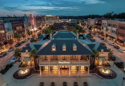 Market Street lit up at sunset in The Woodlands, TX, surrounded by luxury retail and homes in a thriving real estate market