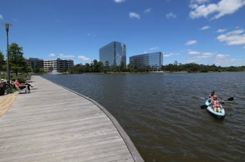 Lake Woodlands with kayakers and modern office buildings in the background