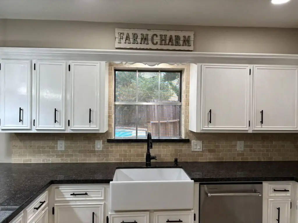 Modern farmhouse kitchen with white cabinets, farmhouse sink, and granite countertops in a Spring, Texas home for sale