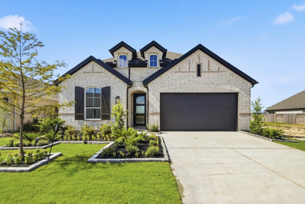 New construction brick home with black trim, two-car garage and landscaped front yard in the Houston area